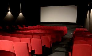 une salle de cinéma, fauteuil rouge, ecran blanc
