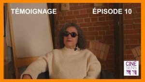 Leïla, cheveux grisonnants, lunettes noires, assises devant un mur de briques ocres.