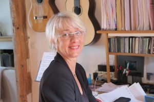 Portrait de la réalisatrice Dominique Fischbach souriante dans un bureau