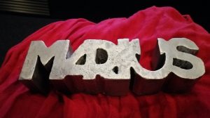 Photographie de la statuette de récompense, inscrite "Marius" en lettre métallique.