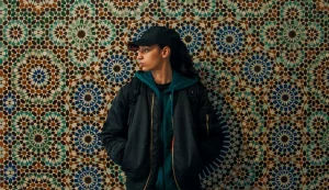 Fatima, la jeune héroïne du film, est adossée à une mosaïque de cercles colorés et regarde dans le vide