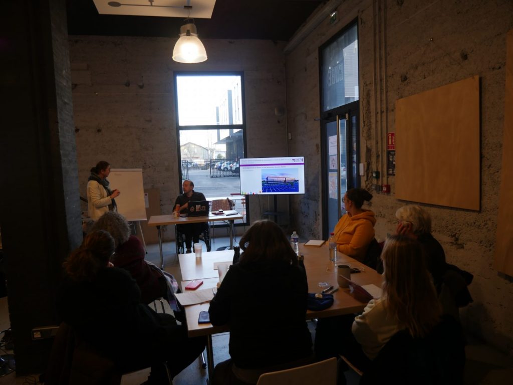 Les participants en cercle autour d'une table face à un intervenant, Didier, derrière son ordinateur.
