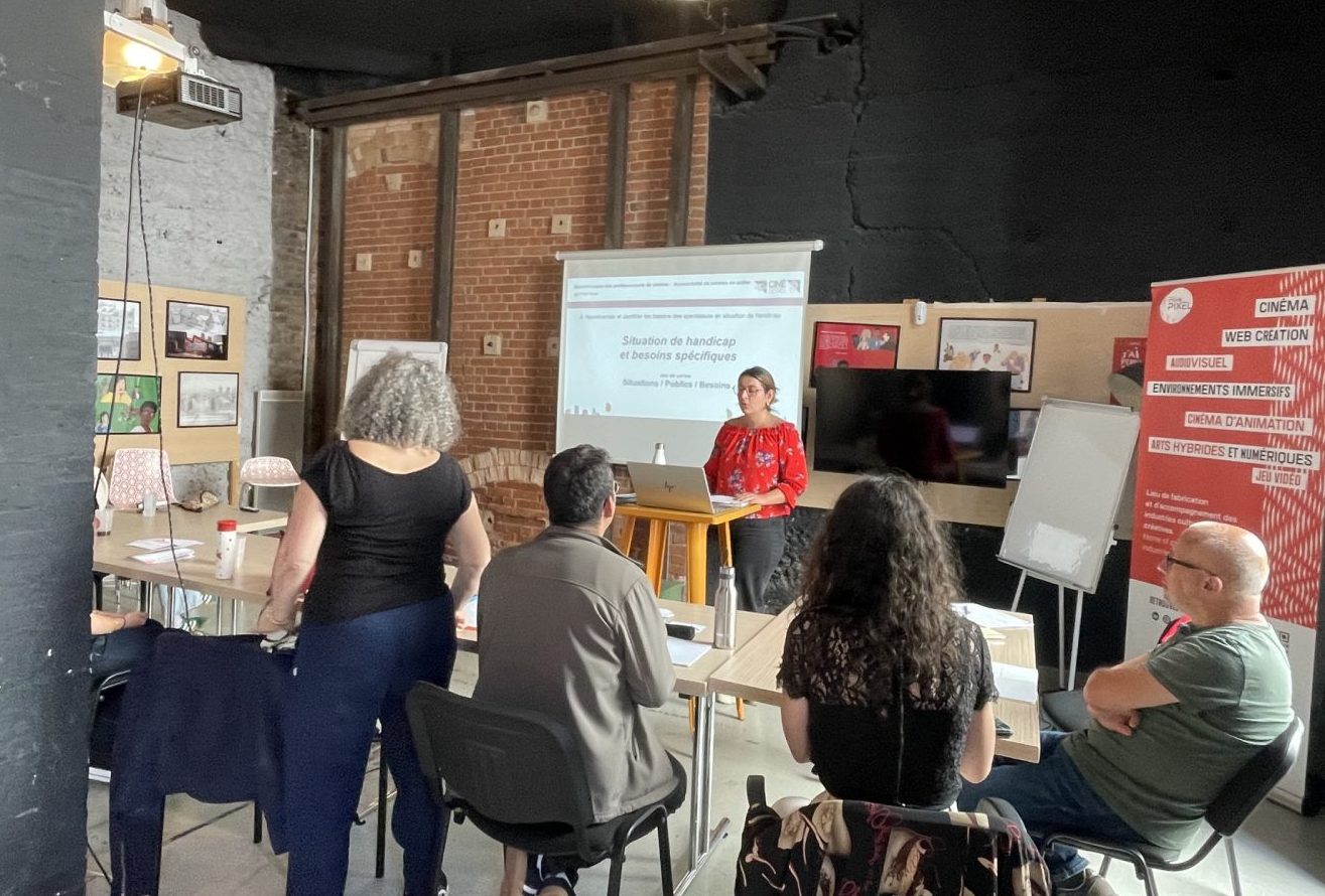 Des participants autour de table écoute l'intervenante qui leur fait face.